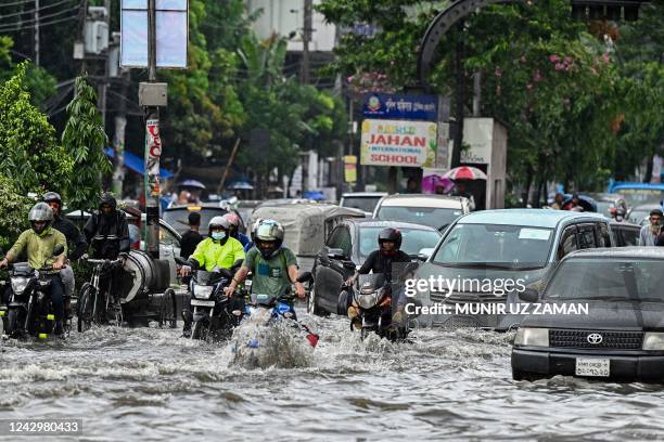 Vehicles and motorists wade through a waterlogged street following heavy monsoon rains in Dhaka on September 6, 2022.