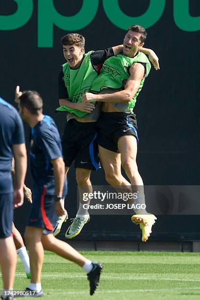 Barcelona's Polish forward Robert Lewandowski and Barcelona's Spanish midfielder Gavi jump as they attend a training session at the Ciudad Deportiva...