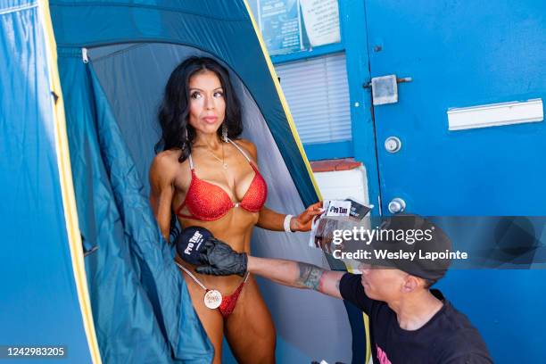 Venice, CA Bodybuilding contestant Gloria Lopez gets manually tanned by her husband, Eric Anderson, at the Muscle Beach Championships on Monday,...