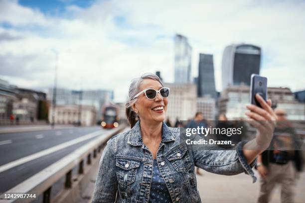 senior female tourist having video call over smart phone - global mindset stock pictures, royalty-free photos & images