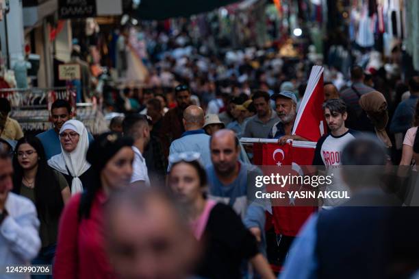 Customers walk past a flag vendor as they shop at a bazaar in Istanbul on September 6 as Turkey's economy is suffering its biggest economic crisis in...