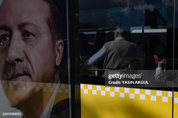 Bus passengers pass by a poster of Turkey's President Recep Tayyip Erdogan in Istanbul on September 6 as Turkey's economy is suffering its biggest...