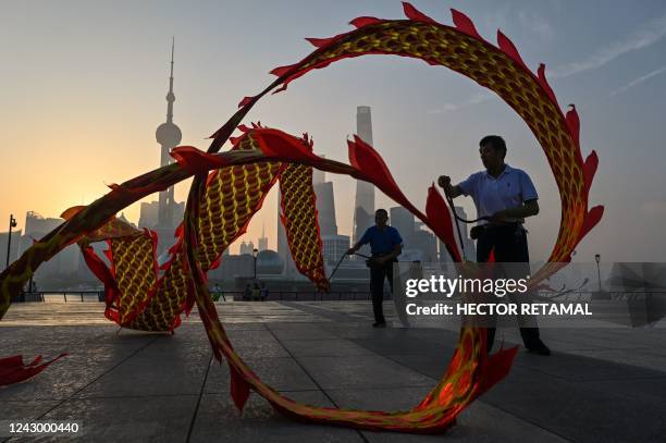 Men twirl dragon streamers on the Bund promenade along the Huangpu River during sunrise in Shanghai on September 7, 2022.