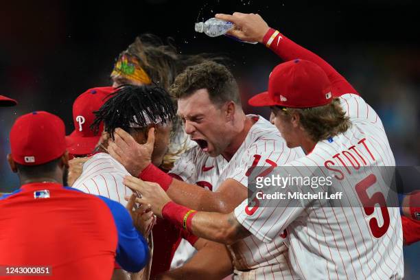 Jean Segura of the Philadelphia Phillies celebrates with Rhys Hoskins and Bryson Stott after hitting the game-winning RBI single in the bottom of the...