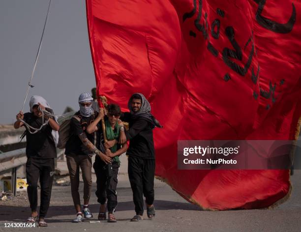 Shi'ite pilgrims carrying a huge religious flag while walking along a road to the city of Nasiriyah during the commemoration of Arbain in the...