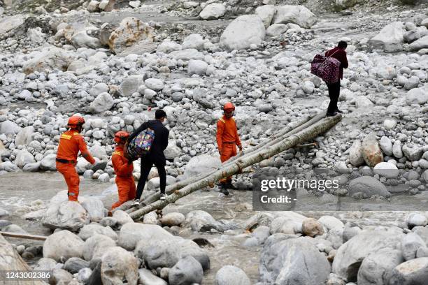 This photo taken on September 6, 2022 shows rescuers assisting people across a makeshift bridge following a 6.6-magnitude earthquake that struck...