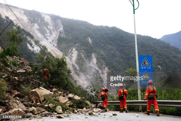 This photo taken on September 6, 2022 shows rescuers walking past fallen rocks from a landslide as they head to an earthquake-affected area following...