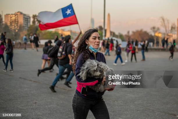 Woman holds her dog as she run away from a police water car in Santiago de Chile, on September 6, 2022. Amid at a protest of college students,...