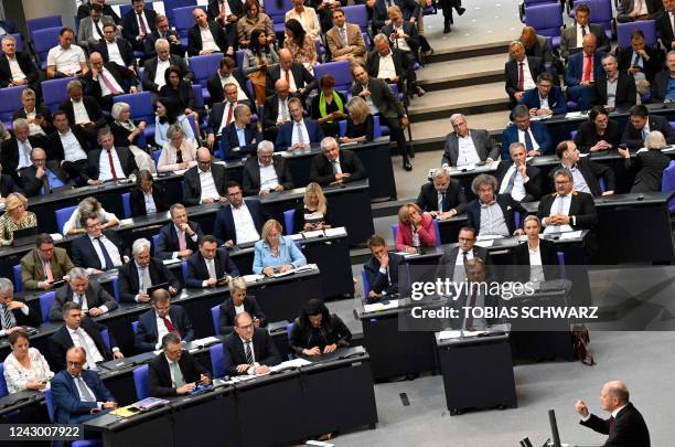 The leader of Germany's conservative Christian Democratic Union party Friedrich Merz looks on as German Chancellor Olaf Scholz addresses delegates...