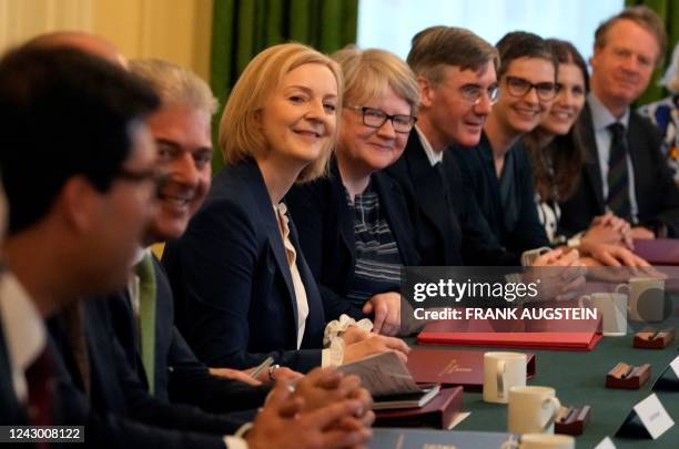 Britain's Prime Minister Liz Truss sits alongside Britain's Health Secretary and deputy Prime Minister Therese Coffey as she poses with members of...