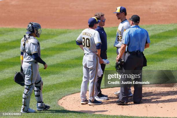 Starting pitcher Eric Lauer of the Milwaukee Brewers talks with Manager Craig Counsell and a member of the training staff before exiting the game in...