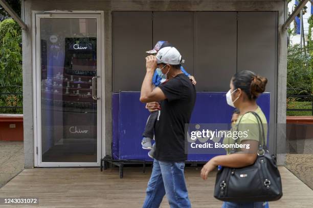 Pedestrians pass a government Chivo Bitcoin automated teller machine kiosk on the one-year anniversary of Bitcoin adoption in Ahuachapan, El...