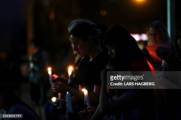 People hold candles during a vigil for the stabbing attack victims in Prince Albert, Saskatchewan, Canada, on September 7, 2022. - The last suspect...
