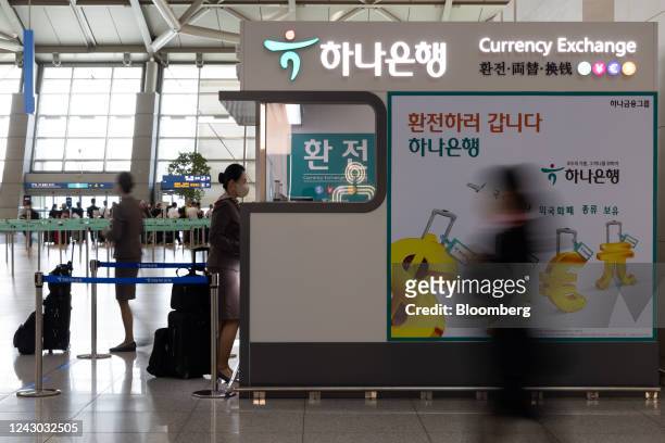 Aa flight attendant in front of a Hana Bank currency exchange booth at Incheon International Airport in Incheon, South Korea, on Thursday, Sept. 8,...