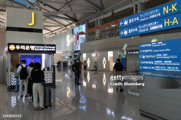 Travelers wait in line at a Woori Bank currency exchange booth at Incheon International Airport in Incheon, South Korea, on Thursday, Sept. 8, 2022....