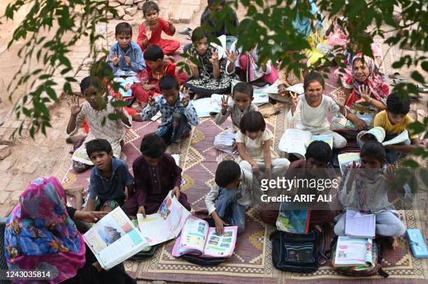 Children of brick kiln workers attend a class at a brick kiln site in Lahore on September 8, 2022.