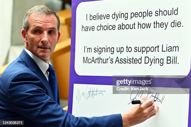 Scottish Liberal Democrat MSP Liam McArthur signs a board in the lobby of the Scottish Parliament for other MSPs to record their support for his...