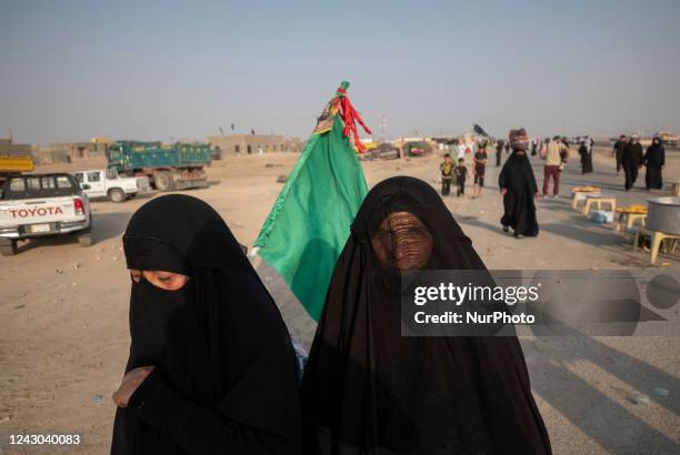 Two Iraqi Shi'ite pilgrims wearing burqa carrying a religious flag while walking along a road in Samawah in the south of Iraq during the...