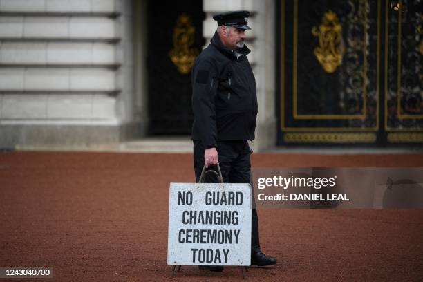 Member of staff holds a board reading "No changing of the guard ceremony today" in the courtyard of Buckingham palace, central London, on September...