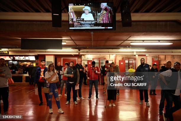 Fans stand beneath a screen display the news that Queen Elizabeth II has died, as they wait ahead of the UEFA Europa League Group E football match...