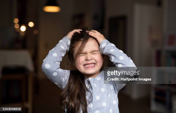 front view portrait of small girl standing indoors at home, gritting teeth. - tantrum stock pictures, royalty-free photos & images