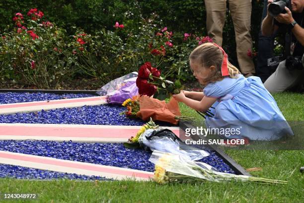 Girl places a bouquet of flowers on a British flag outside the British Embassy in Washington, DC, on September 8 following the death of Queen...