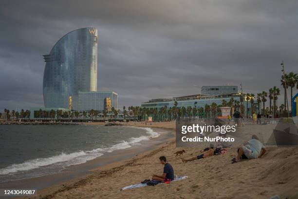 Group of people rests on the sand of a beach near the W hotel, after a stormy afternoon, in Barcelona, on September 2, 2022.