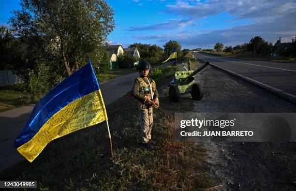 Ukrainian child holds a mock rifles while manning an improvised checkpoint the Donetsk region of Ukraine, on September 8 amid the Russian invasion of...