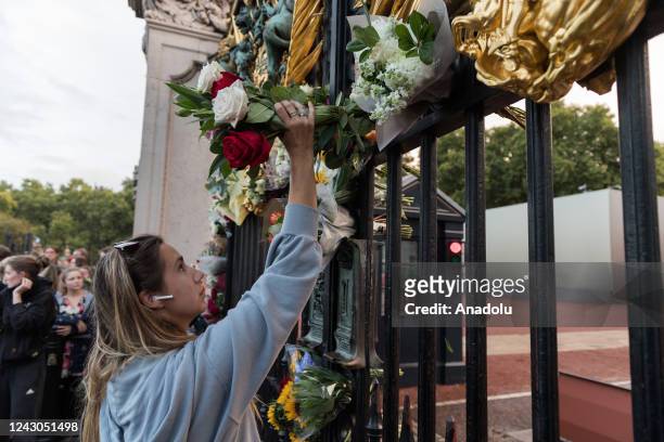 Woman places a bouquet of flowers at the gate of Buckingham Palace following the announcement of the death of Queen Elizabeth II in London, United...