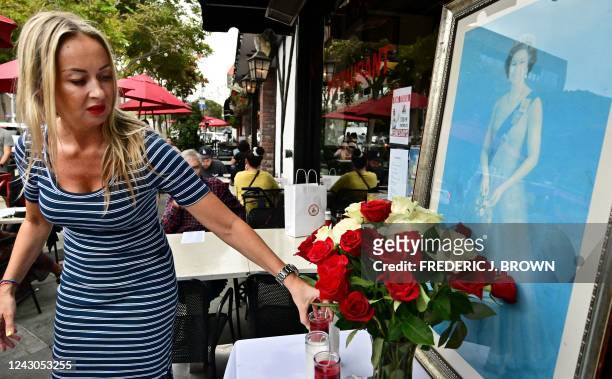 Lisa Powers sets up a display of roses and candles beside a portrait of the late Queen Elizabeth II outside a British pub in Santa Monica,...