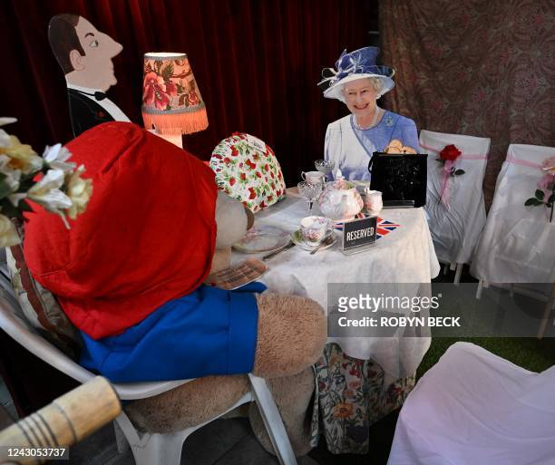 Life size cardboard cut out of Queen Elizabeth II with Paddington Bear seated at a table for tea is on display at the Rose Tree Cottage English Tea...