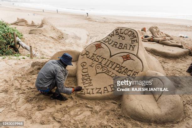 South African sand sculptor gives final touches showing the a message of the passing of Queen Elisabeth II on the South beach in Durban, on September...