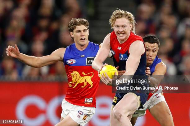 Clayton Oliver of the Demons is tackled by Hugh McCluggage and Deven Robertson of the Lions during the 2022 AFL Second Semi Final match between the...