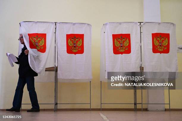 Man leaves a voting booth during the Moscow municipal deputies elections at a polling station in Moscow on September 9, 2022. - Russians in several...