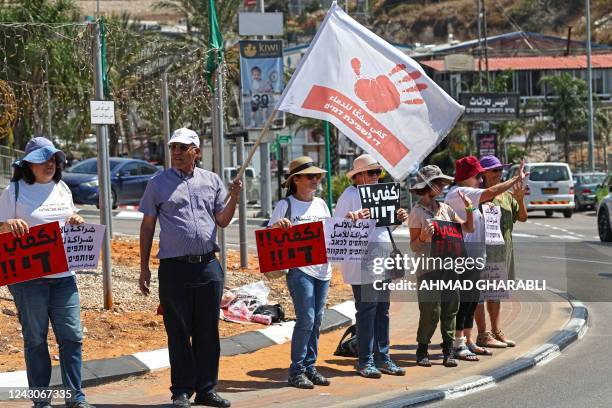 Arab Israeli citizens and activists lift placards at a rally in the mostly-Arab northern city of Umm al-Fahm on September 9 to denounce crime and...