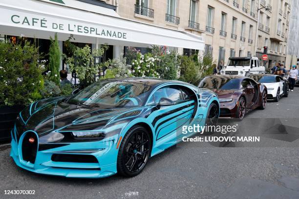This photograph taken on September 8, 2022 shows Bugatti Chiron sports cars parked in front of "Cafe de l'Esplanade", in Paris.