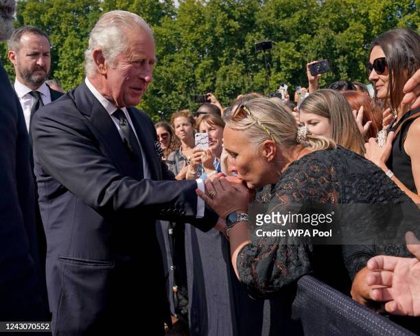 Well-wisher kisses the hand of King Charles III during a walkabout outside Buckingham Palace, London, to view messages and tributes following the...