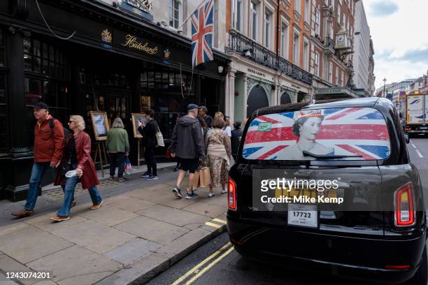 Image of Queen Elizabeth II and a Union Flag in the back window of a black taxi cab on the day following her death on 9th September 2022 in London,...