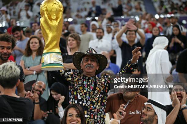 Fan carries a replica of the World Cup Trophy during the Lusail Super Cup football match between Saudi Arabia's Al-Hilal and Egypt's Zamalek at the...