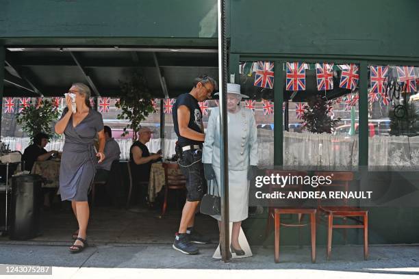 Woman walks past a life-sized cut-out of Britain's Queen Elizabeth II displayed outside the British owned business of Tea & Sympathy in Manhattans...