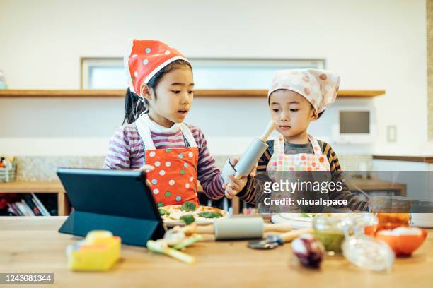 kinder, die kochanweisungen aus dem internet ansehen. - children cooking school stock-fotos und bilder