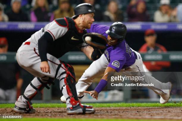 Elehuris Montero of the Colorado Rockies slides in to score ahead of the tag by Carson Kelly of the Arizona Diamondbacks in the seventh inning at...