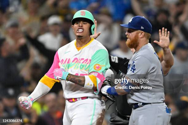 Manny Machado of the San Diego Padres celebrates after hitting an RBI triple as Justin Turner of the Los Angeles Dodgers looks on during the fifth...