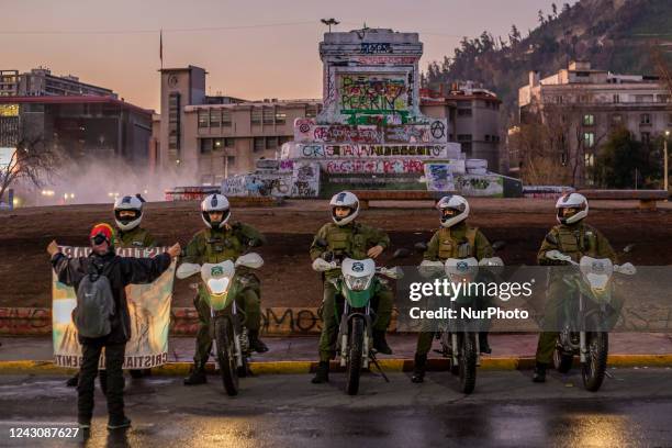 Woman holds a banner in front of a motorized police squad located at Plaza de la Dignidad in Santiago de Chile, on September 9, 2022. During the...