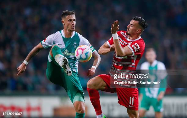 Marco Friedl of Bremen fights for the ball with Mergim Berisha of Augsburg during the Bundesliga match between SV Werder Bremen and FC Augsburg at...