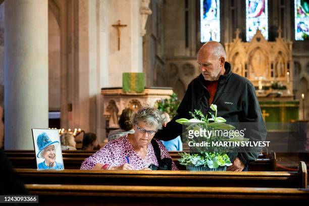 Queen Elizabeth's picture is seen among church pews as people come to St. Alban's English Church to pay their respect, pray and write messages of...