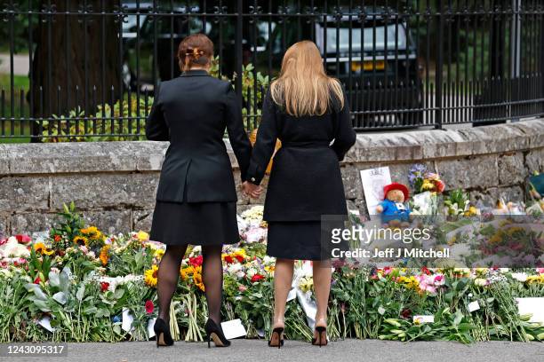 Princess Eugenie of York and Princess Beatrice of York hold hands as they look at floral tributes outside Crathie Kirk church on September 10, 2022...