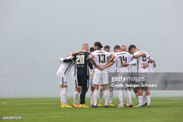 Players of Elversberg stand in a circle while fans of 1860 set off smoke bombs prior to the 3. Liga match between SV 07 Elversberg and TSV 1860...
