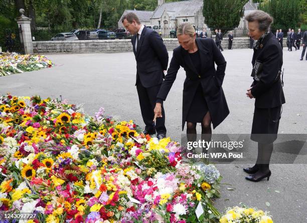 Peter Phillips, Zara Tindall, and Princess Anne, Princess Royal look at messages and floral tributes left by members of the public after attending a...