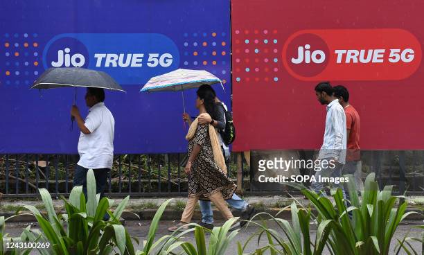 People walk past Jio 5G branding in Mumbai. Reliance Jio 5G network service is set to roll out in the month of October 2022. Initially the 5G service...